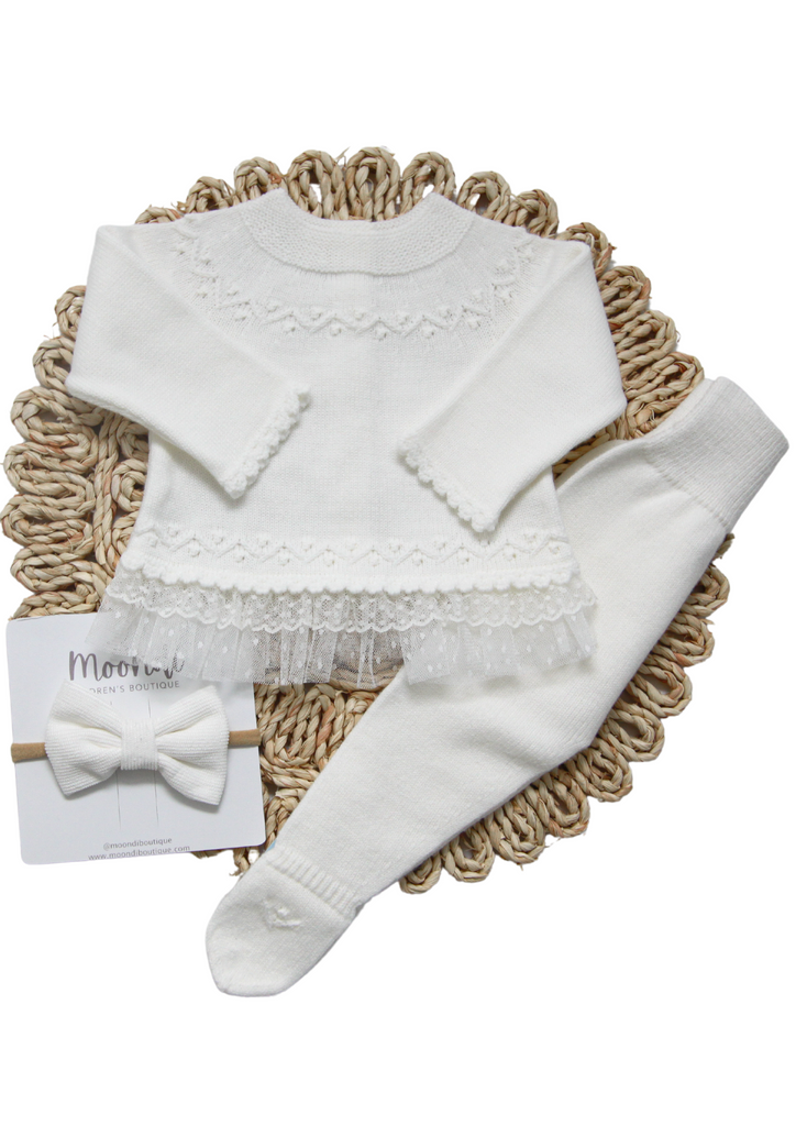 Beautiful white, old rose or green two-piece set for girls from Artesania Granlei. The top has a delicate knit pattern around the neckline, cuffs, and hem, with delicate ruffled voile trim. The pants have knitted detail on the feet.